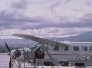 A small plane with a cloudy sky and distant mountains in the background.